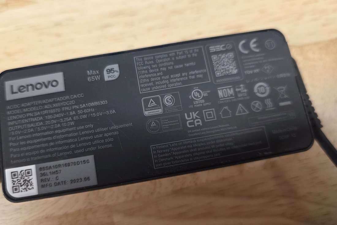Label side of a genuine Lenovo 65 W USB-C adapter showing model number, wattage and dense certification marks